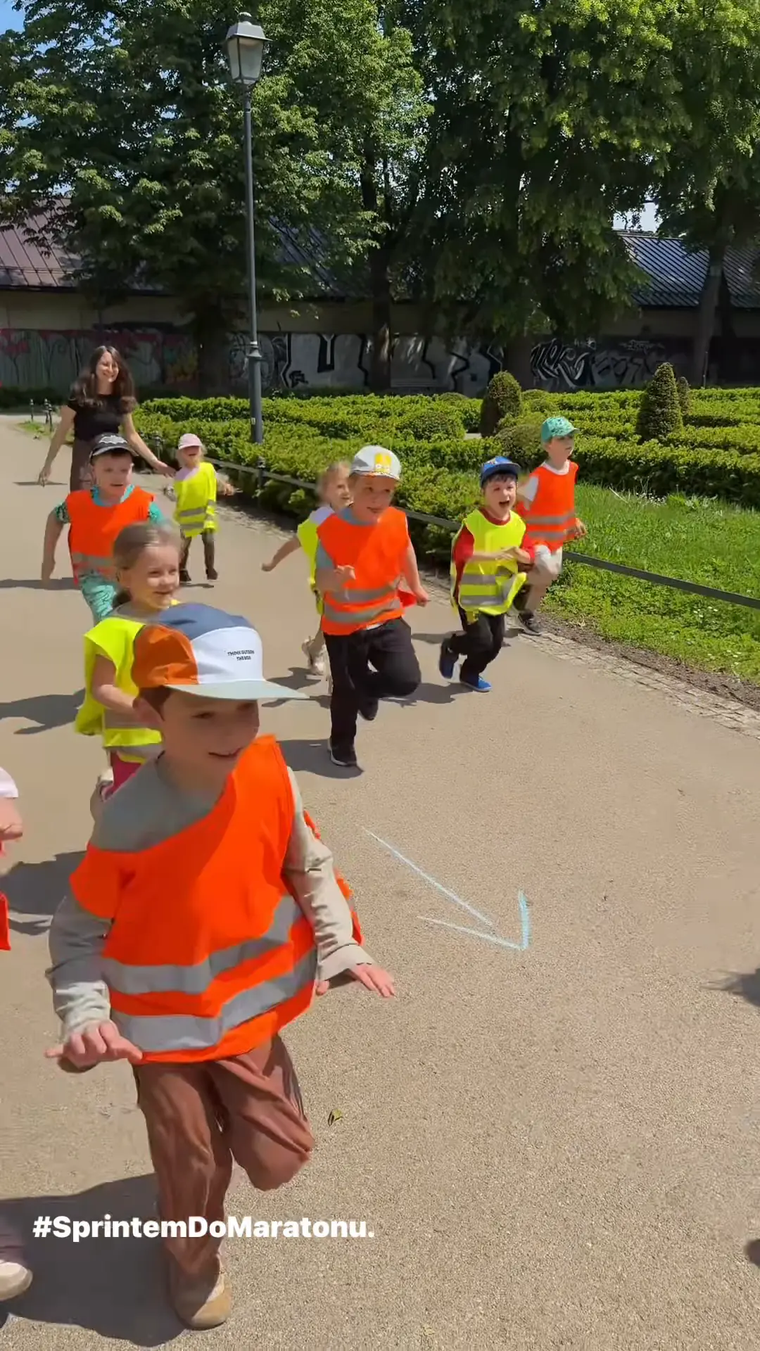 Chłopiec w pomarańczowej kamizelce biegnie parkową alejką podczas akcji Sprintem do maratonu