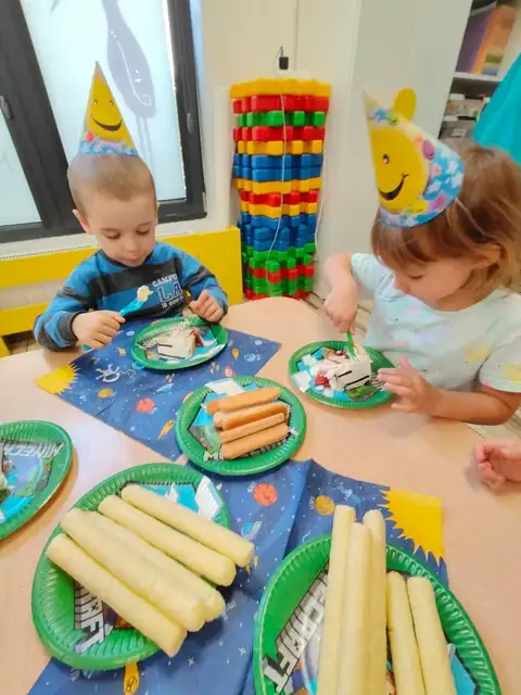 Przedszkolaki w urodzinowych czapeczkach przy stole