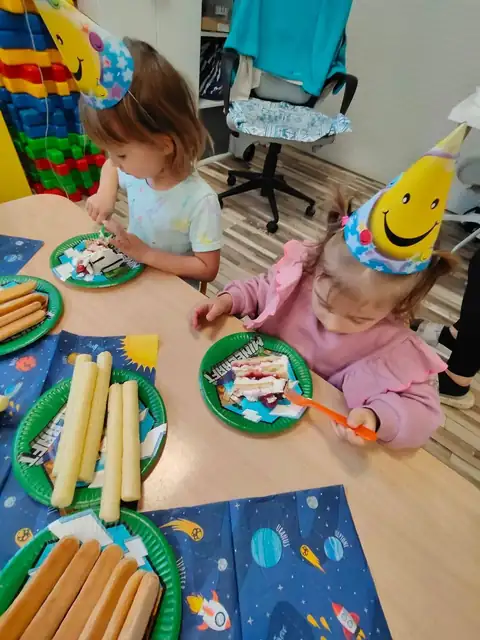 Przedszkolaki w urodzinowych czapeczkach przy stole