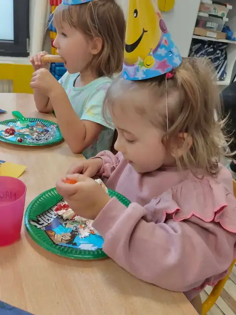 Przedszkolaki w urodzinowych czapeczkach przy stole