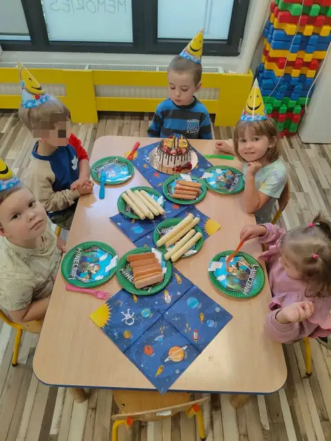 Przedszkolaki w urodzinowych czapeczkach przy stole