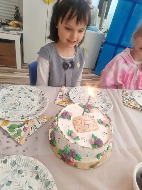 Solenizantka zdmuchuje świeczkę na urodzinowym torcie
