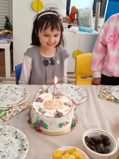 Solenizantka zdmuchuje świeczkę na urodzinowym torcie